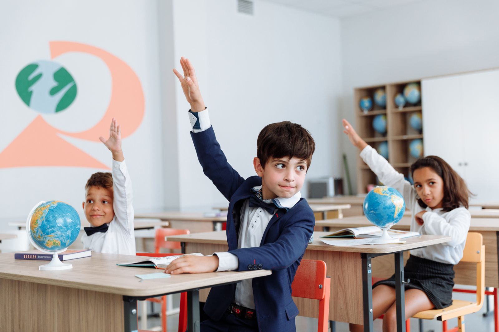 A student raising his hand in a classroom